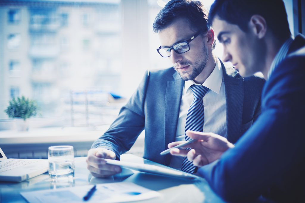 Image of two young businessmen discussing project at meeting